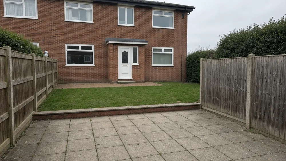 Example image: buff slab patio with a step up to a lawn behind a 1960s semi-detached house